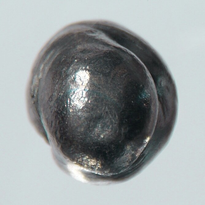 Metaliczny beryl. Jądro berylu-9 jest słabo związane i pod wpływem cząstki alfa łatwo oddaje neutron w reakcji `⁹Be + α → ¹²C + n` — tej samej, którą Chadwick odkrył neutron w 1932 roku. Beryl był „dawcą" neutronów w inicjatorze. Zdjęcie: Wikimedia Commons